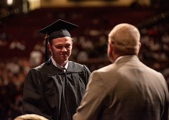 Students partipate in walking to graduate from the College of Business and Communication.