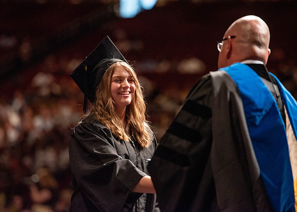 Students partipate in walking to graduate from the College of Business and Communication.
