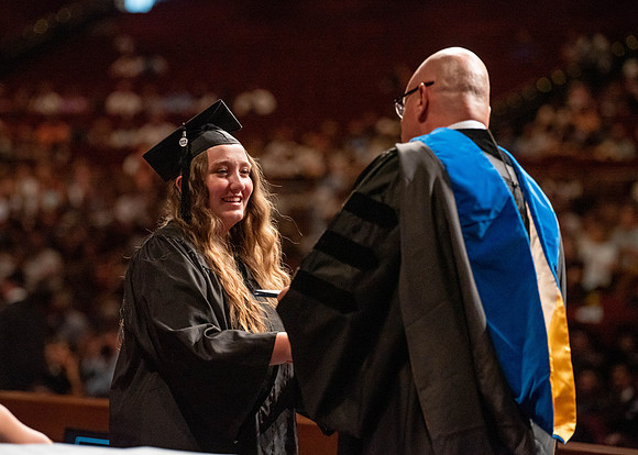 Students partipate in walking to graduate from the College of Business and Communication.