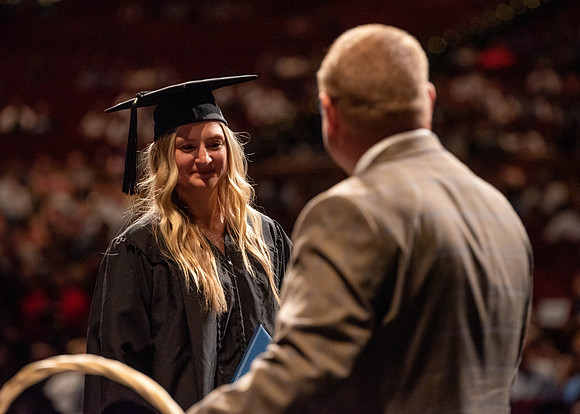 Students partipate in walking to graduate from the College of Business and Communication.