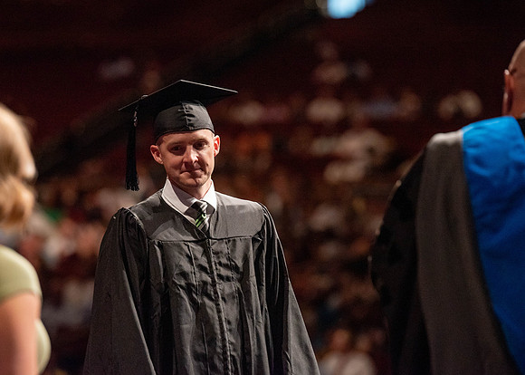 Students partipate in walking to graduate from the College of Business and Communication.