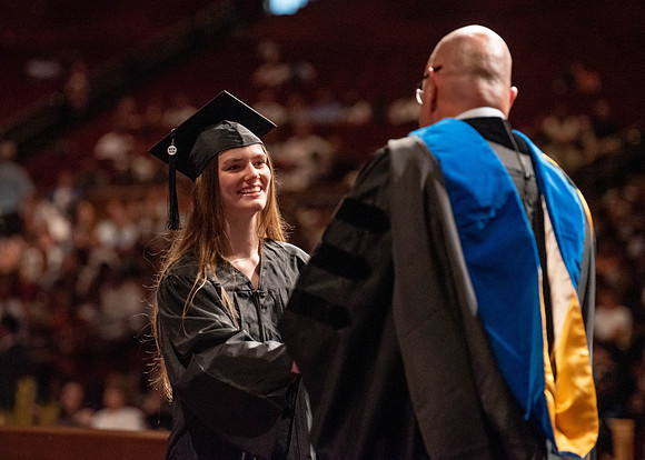 Students partipate in walking to graduate from the College of Business and Communication.