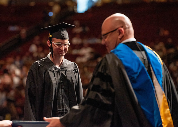 Students partipate in walking to graduate from the College of Business and Communication.