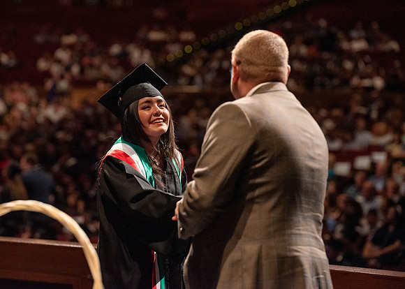 Students partipate in walking to graduate from the College of Business and Communication.