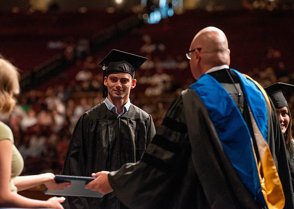 Students partipate in walking to graduate from the College of Business and Communication.