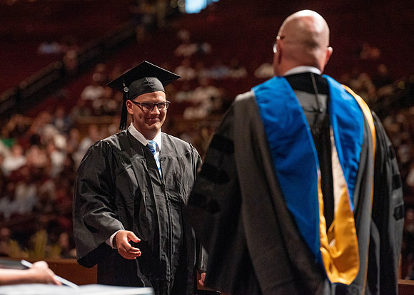 Students partipate in walking to graduate from the College of Business and Communication.