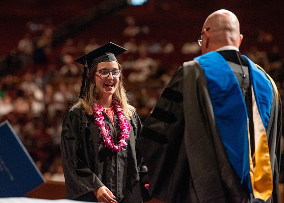 Students partipate in walking to graduate from the College of Business and Communication.