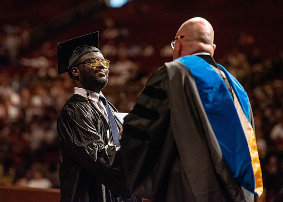 Students partipate in walking to graduate from the College of Business and Communication.