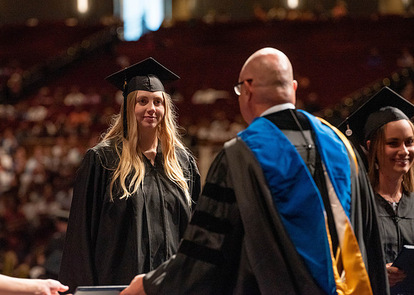 Students partipate in walking to graduate from the College of Business and Communication.