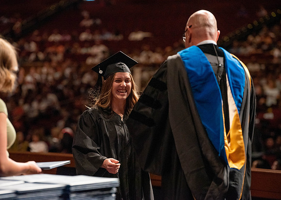 Students partipate in walking to graduate from the College of Business and Communication.