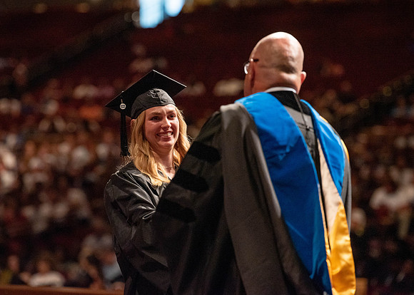 Students partipate in walking to graduate from the College of Business and Communication.