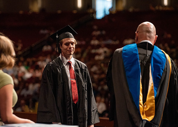 Students partipate in walking to graduate from the College of Business and Communication.