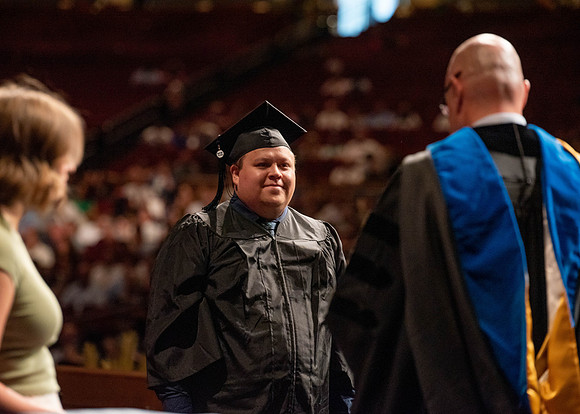 Students partipate in walking to graduate from the College of Business and Communication.
