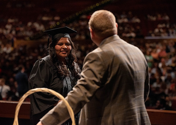 Students partipate in walking to graduate from the College of Business and Communication.