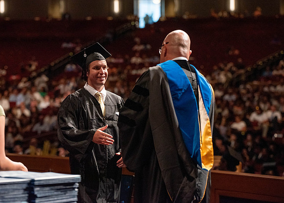 Students partipate in walking to graduate from the College of Business and Communication.