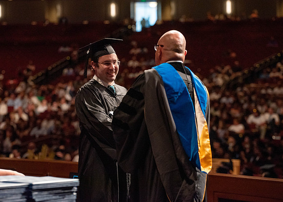 Students partipate in walking to graduate from the College of Business and Communication.