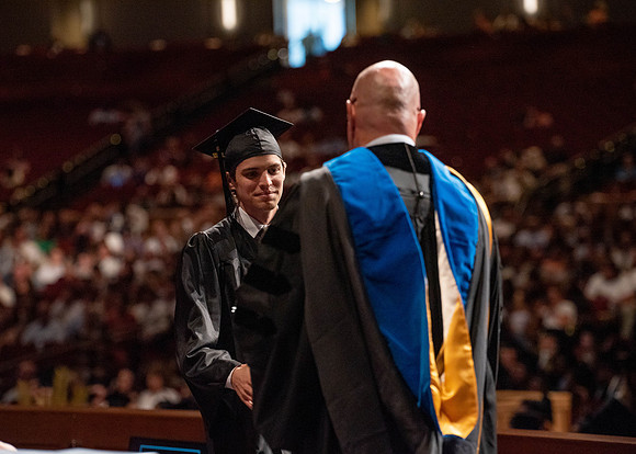 Students partipate in walking to graduate from the College of Business and Communication.