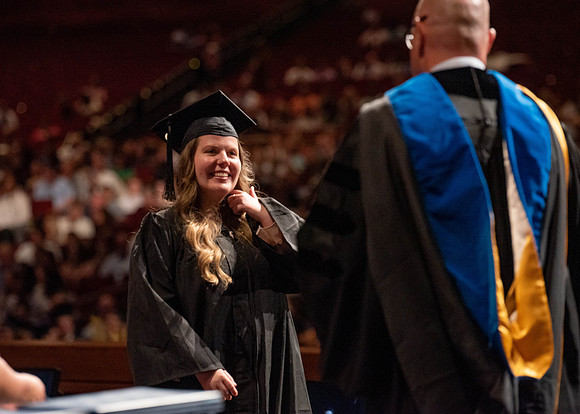 Students partipate in walking to graduate from the College of Business and Communication.