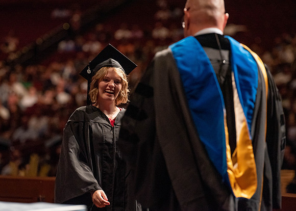 Students partipate in walking to graduate from the College of Business and Communication.