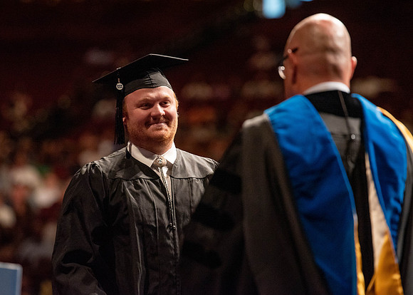 Students partipate in walking to graduate from the College of Business and Communication.
