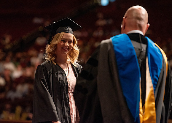 Students partipate in walking to graduate from the College of Business and Communication.