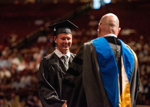 Students partipate in walking to graduate from the College of Business and Communication.