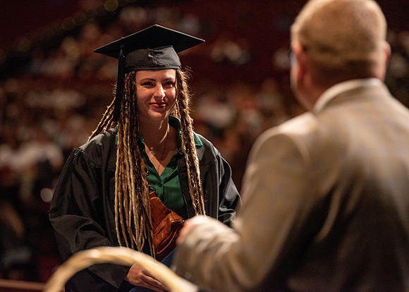 Students partipate in walking to graduate from the College of Business and Communication.