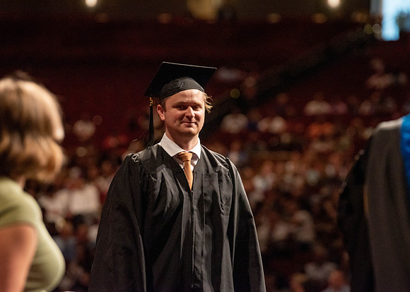 Students partipate in walking to graduate from the College of Business and Communication.