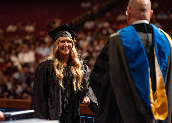 Students partipate in walking to graduate from the College of Business and Communication.