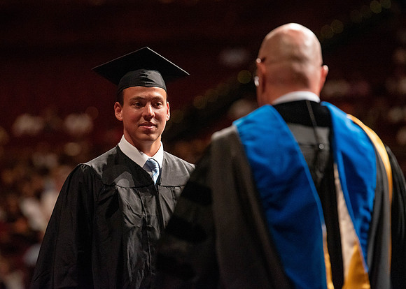 Students partipate in walking to graduate from the College of Business and Communication.