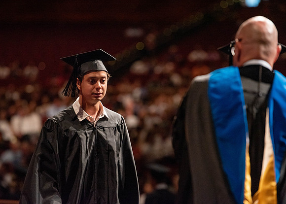 Students partipate in walking to graduate from the College of Business and Communication.