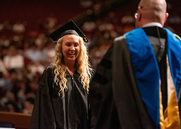Students partipate in walking to graduate from the College of Business and Communication.