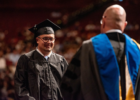 Students partipate in walking to graduate from the College of Business and Communication.