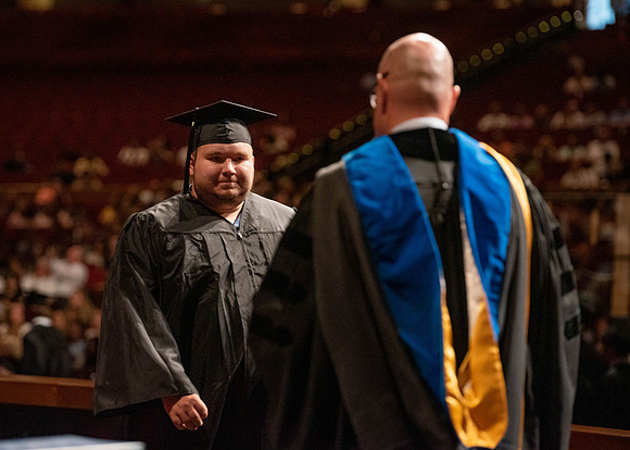 Students partipate in walking to graduate from the College of Business and Communication.