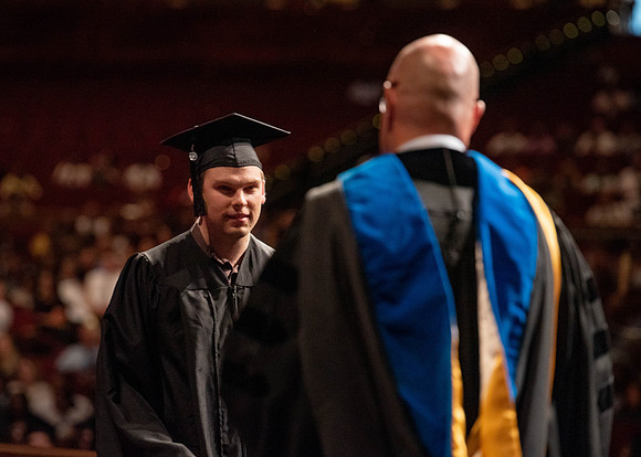Students partipate in walking to graduate from the College of Business and Communication.