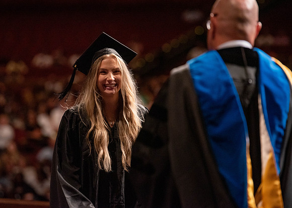 Students partipate in walking to graduate from the College of Business and Communication.