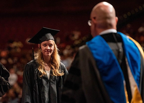 Students partipate in walking to graduate from the College of Business and Communication.