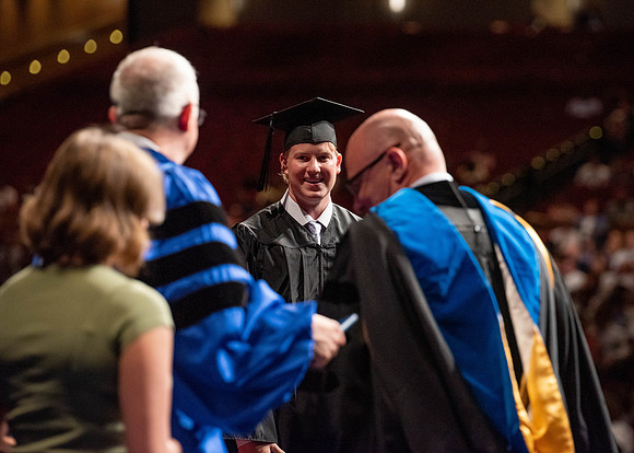 Students partipate in walking to graduate from the College of Business and Communication.