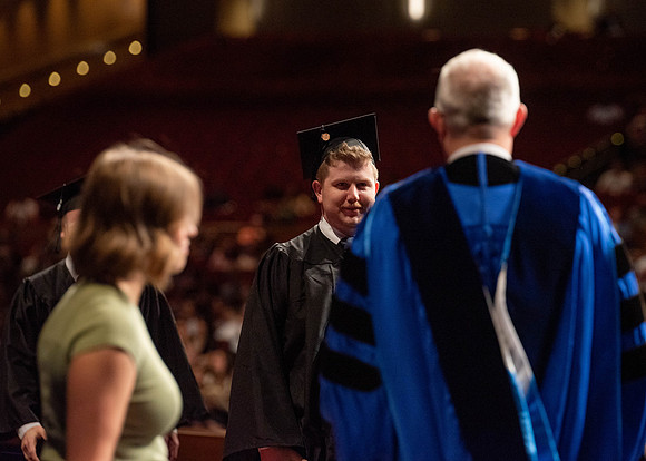 Students partipate in walking to graduate from the College of Business and Communication.