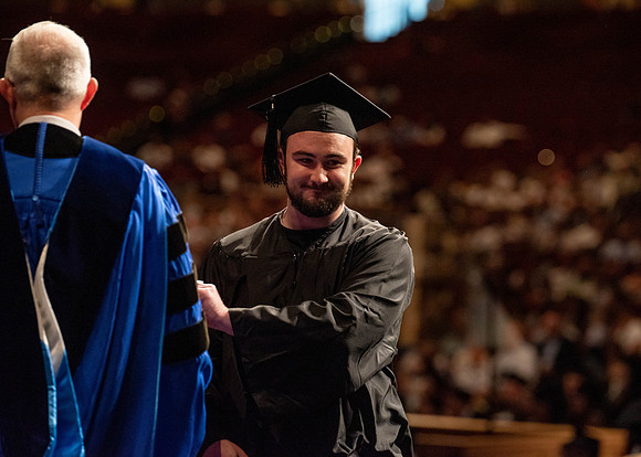 Students partipate in walking to graduate from the College of Business and Communication.