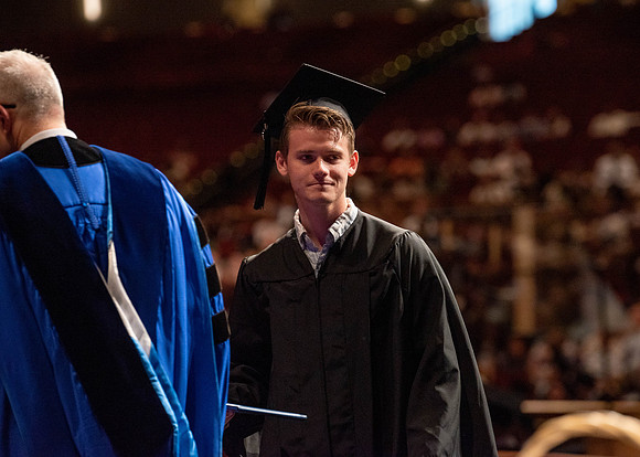 Students partipate in walking to graduate from the College of Business and Communication.