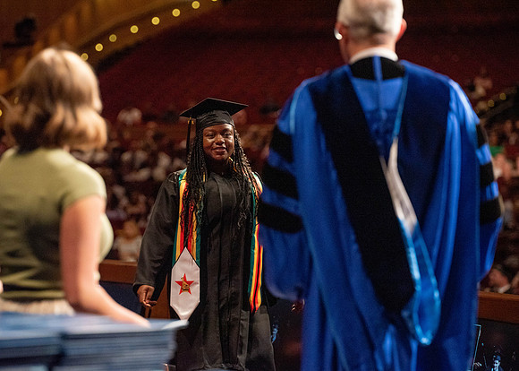 Students partipate in walking to graduate from the College of Business and Communication.