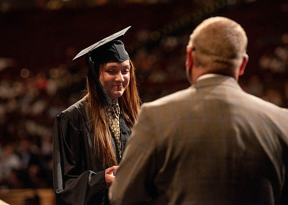 Students partipate in walking to graduate from the College of Business and Communication.