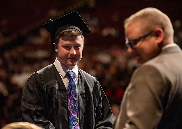 Students partipate in walking to graduate from the College of Business and Communication.