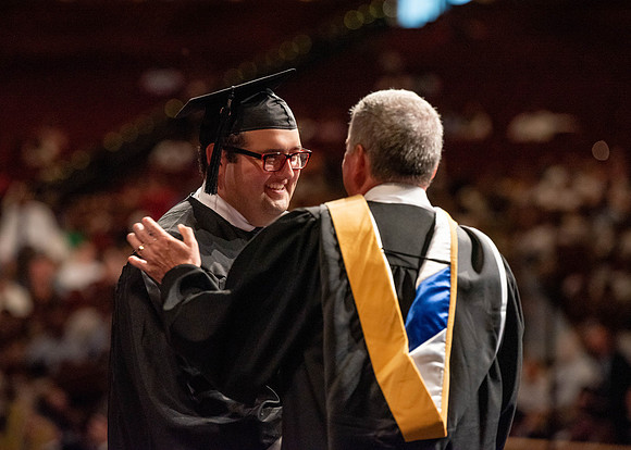 Students partipate in walking to graduate from the College of Business and Communication.
