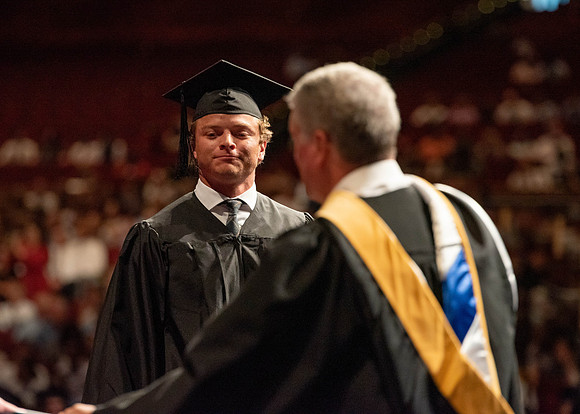 Students partipate in walking to graduate from the College of Business and Communication.