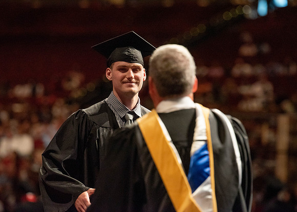 Students partipate in walking to graduate from the College of Business and Communication.