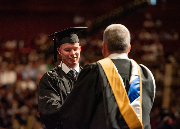 Students partipate in walking to graduate from the College of Business and Communication.