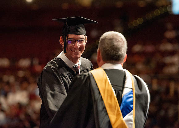 Students partipate in walking to graduate from the College of Business and Communication.