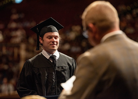 Students partipate in walking to graduate from the College of Business and Communication.
